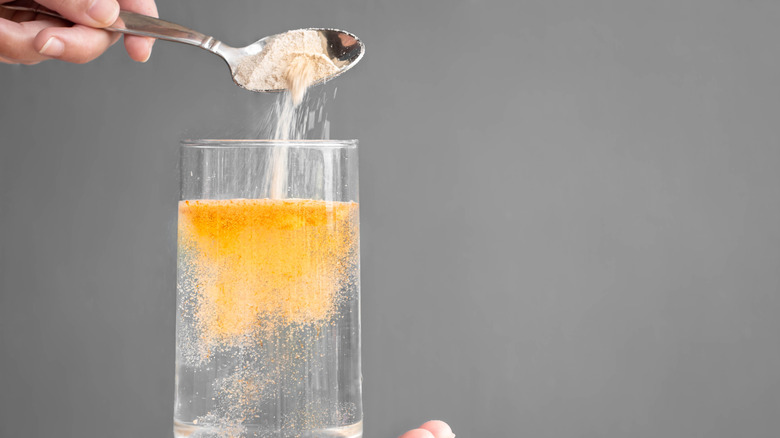 A spoon pouring electrolytes into a glass of water