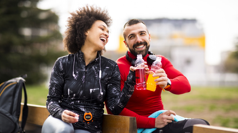 A couple toasting their sports drink bottles after a workout