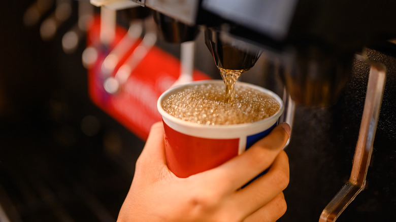 man pouring soda into cup