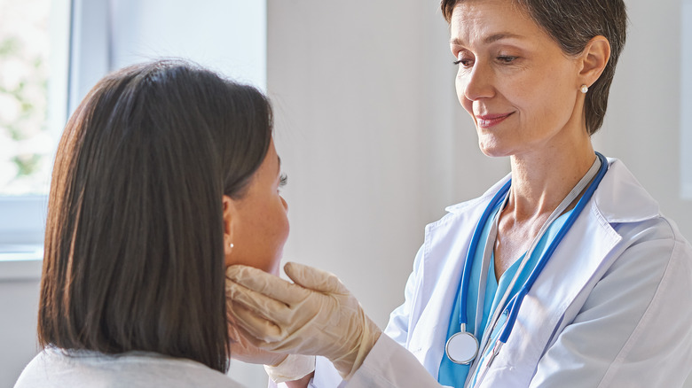 Doctor assessing neck and throat of patient