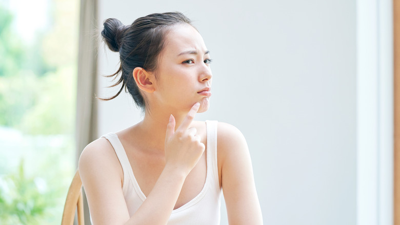 woman looking at skin in mirror