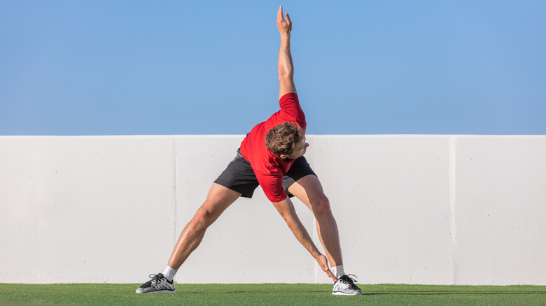 athlete doing a dynamic stretch bending towards one leg