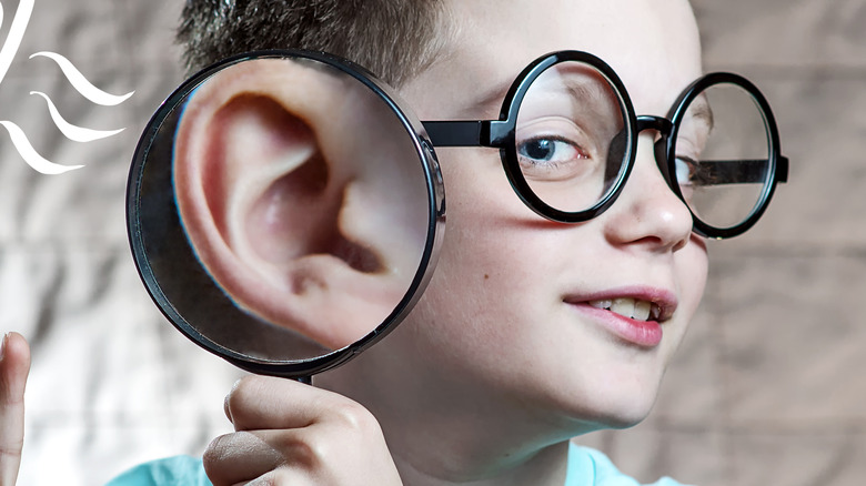 boy holding magnifying glass to ear