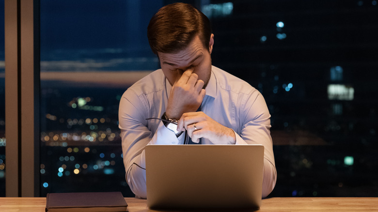 Man at computer rubbing eyes