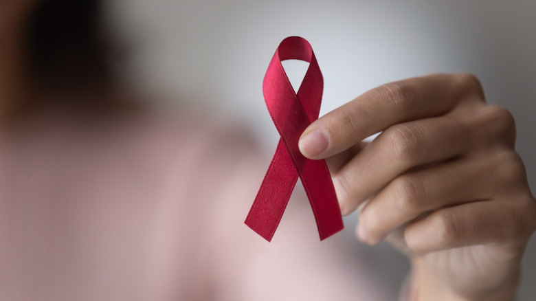 Someone holds a red HIV/AIDS ribbon