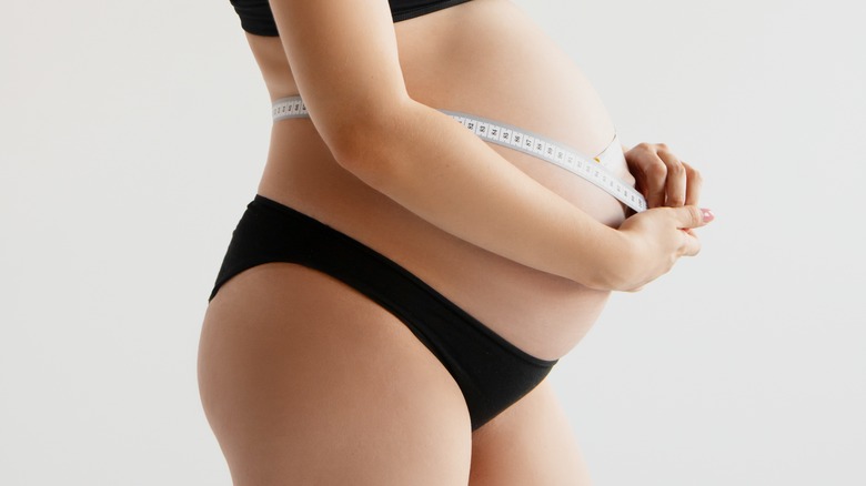 Pregnant woman measuring her belly.