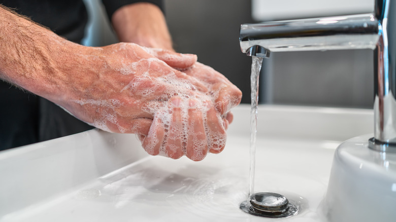 man washing hands at sink