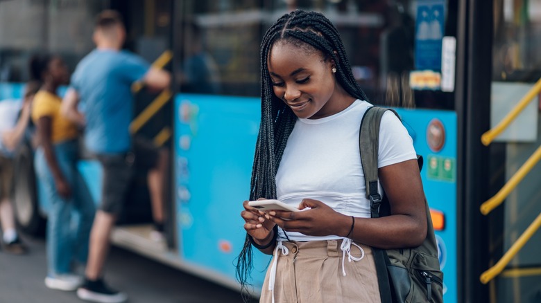 Woman by a bus checking her smartphone