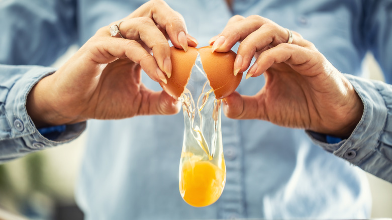 man's hands cutting into plate of eggs