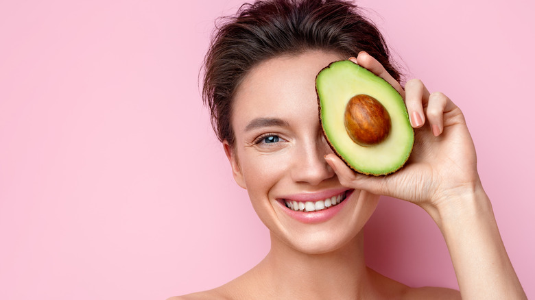 woman holding avocado by face