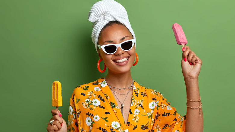 woman holding two colorful popsicles