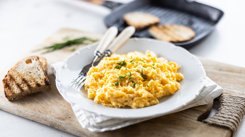 scrambled eggs on a plate with whole grain bread