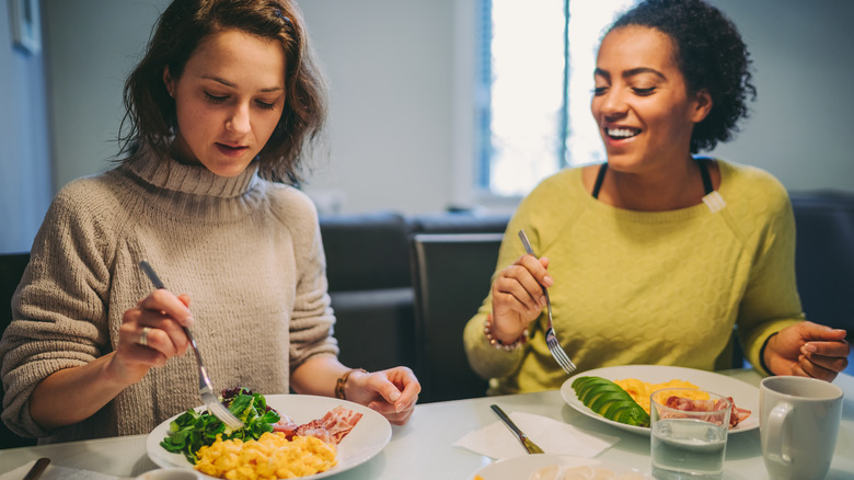 two young women eating eggs for breakfast