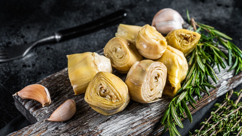 artichoke hearts on a cutting board with rosemary and garlic