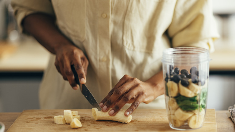 Hands cutting up banana for smoothie