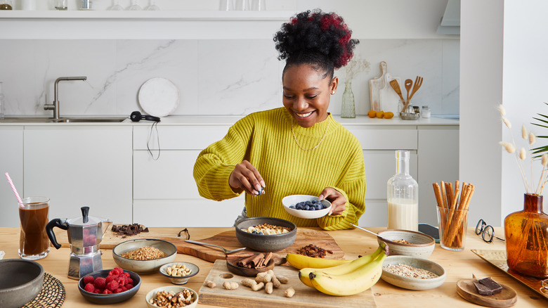 woman adding fruit and nuts to her oatmeal