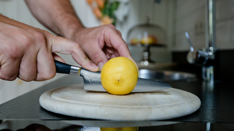 Hands slicing lemon with knife