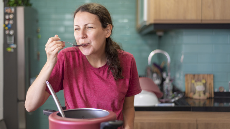 woman tasting what she's cooking in a pot