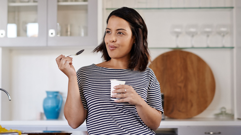 woman eating yogurt in her kitchen