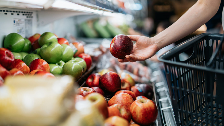 person picks up an apple at the grocery store