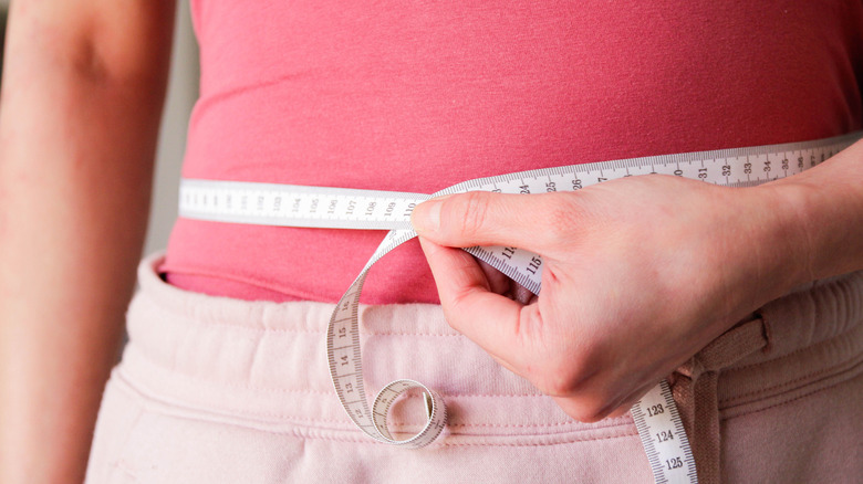 hand holding measuring tape against waist