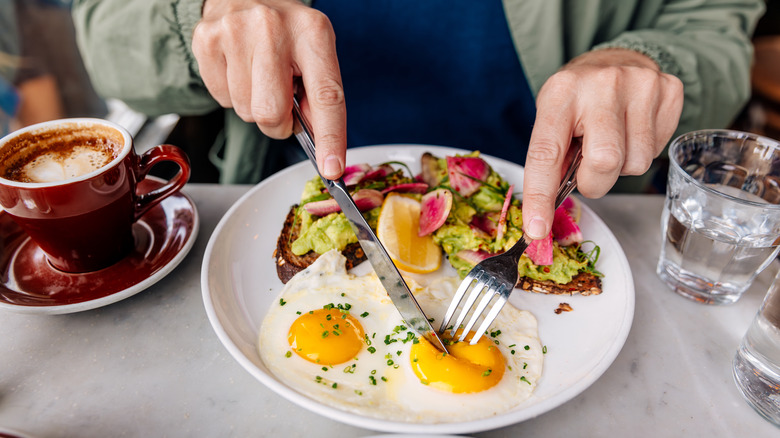 hands slicing into eggs over easy