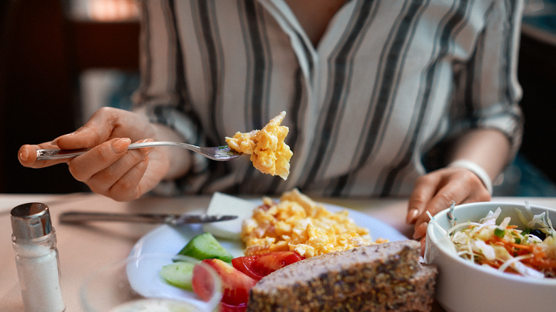 Hand holding a fork with scrambled eggs