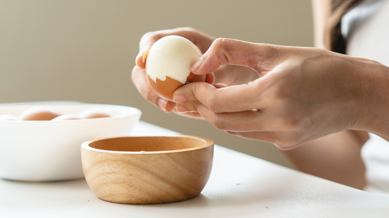 A woman peeling a hard boiled egg