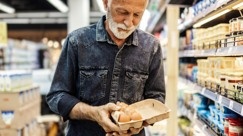 A senior man choosing eggs at the supermarket