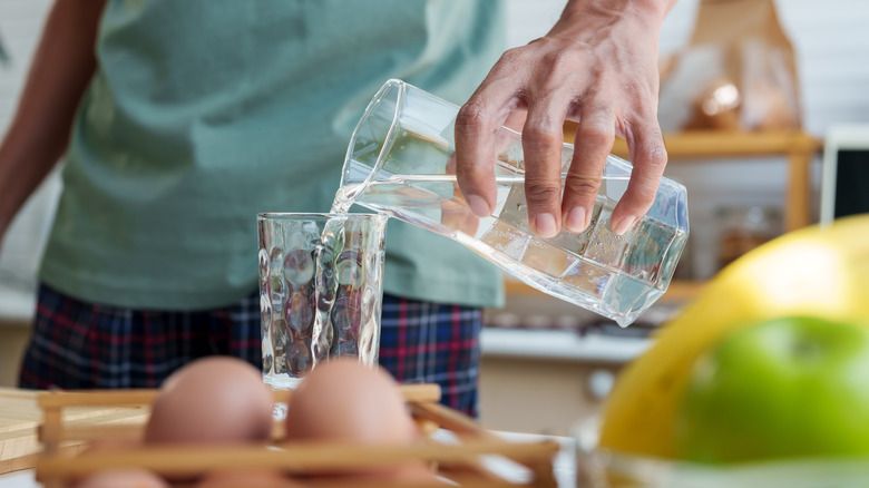 man pouring water into glass with eggs in picture