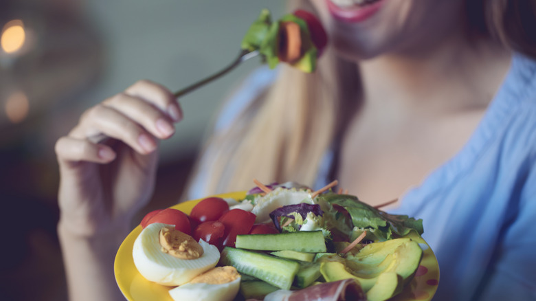 woman eating plate with salad and hard boiled eggs