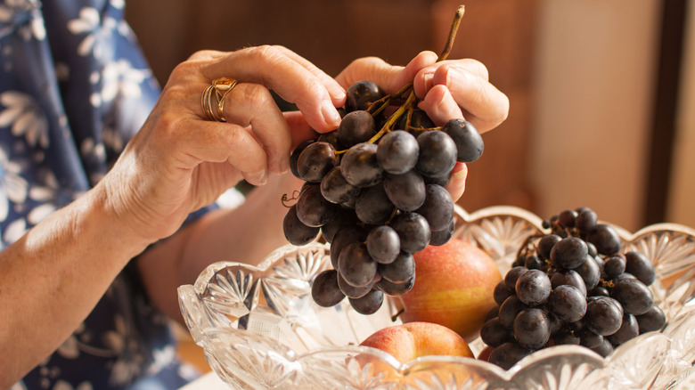 older woman handling bunch of red and purple grapes