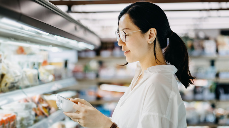 A woman looking at a carton of yogurt at the store