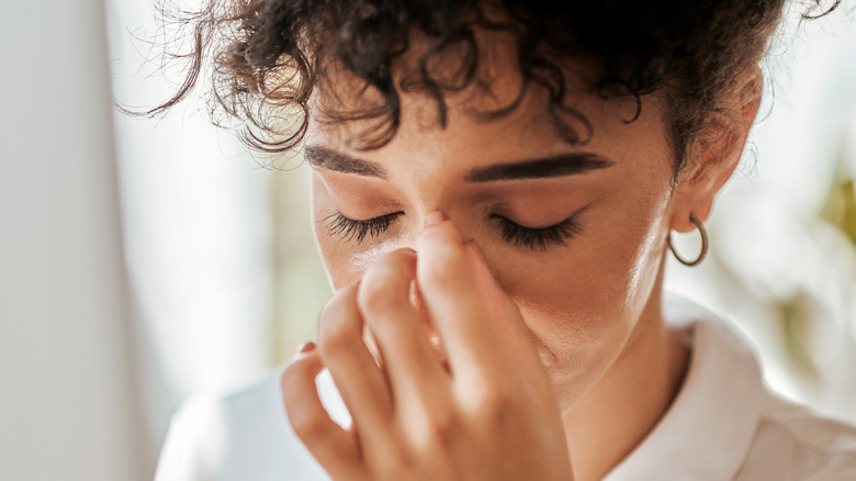 curly-haired woman rubbing nasal bridge