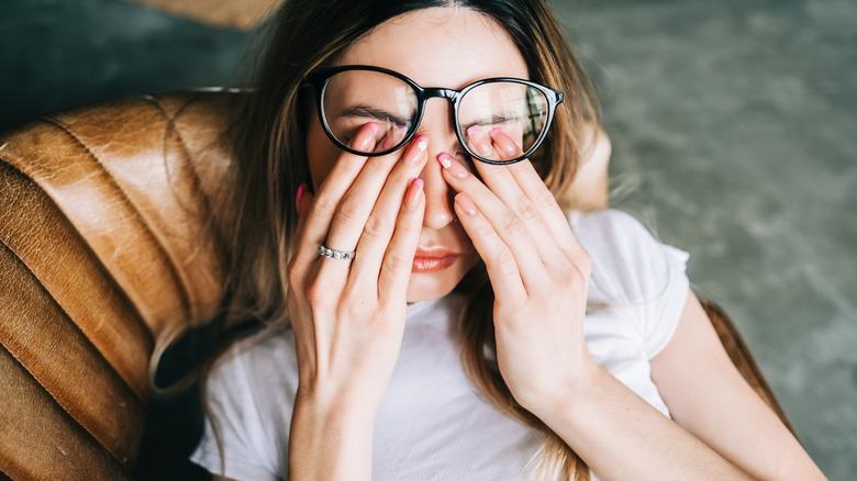 woman with glasses rubbing eyes