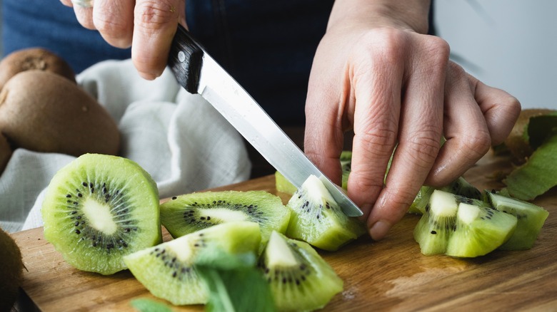 Hand cutting kiwi slices with knife