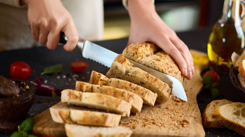 A person slicing bread on a cutting board