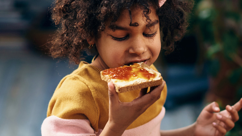 A child eating buttered toast with jam