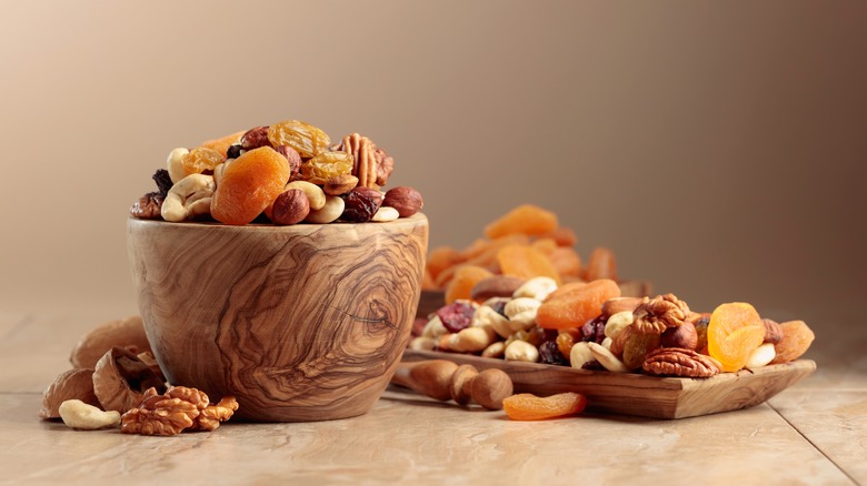 a wooden bowl and tray of nuts and dried apricots