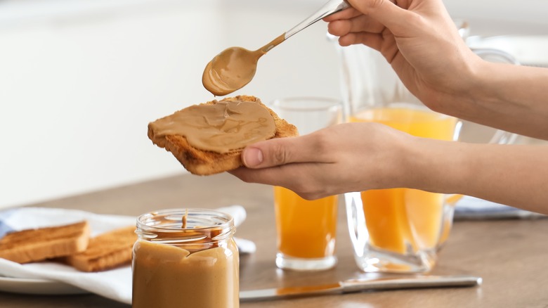 person spreading peanut butter on bread