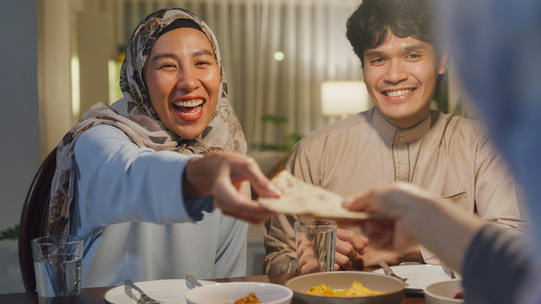 woman receiving pita from someone across table