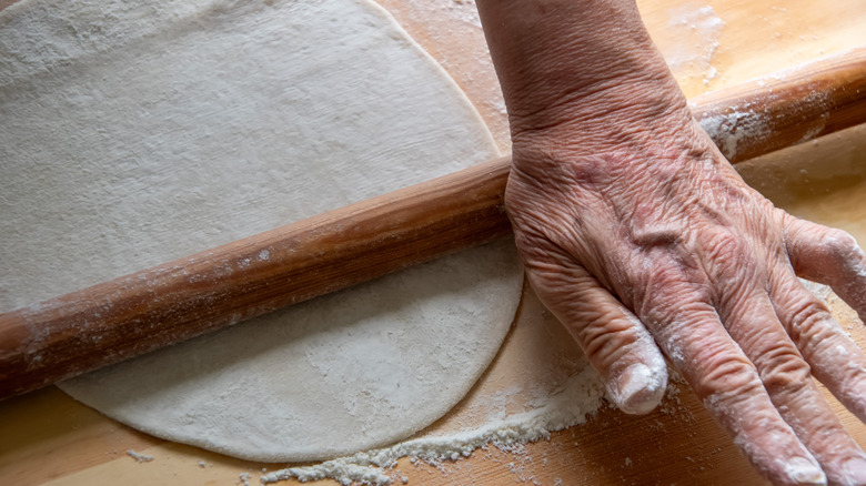 woman's hand rolling bread dough