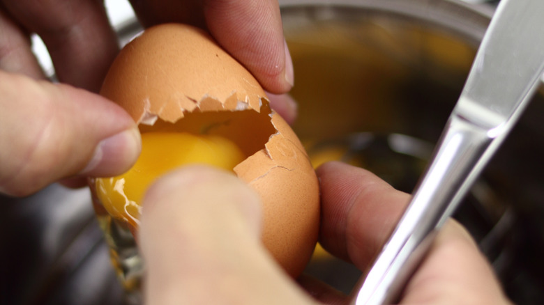 man cracking egg into pot