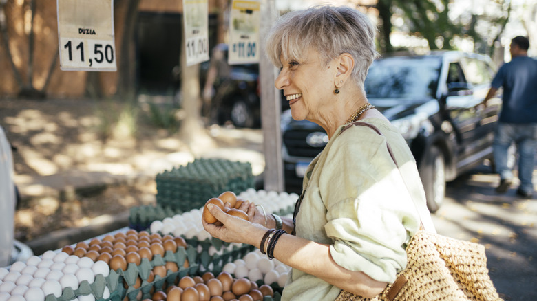 older woman buying eggs at outdoor vendor stand