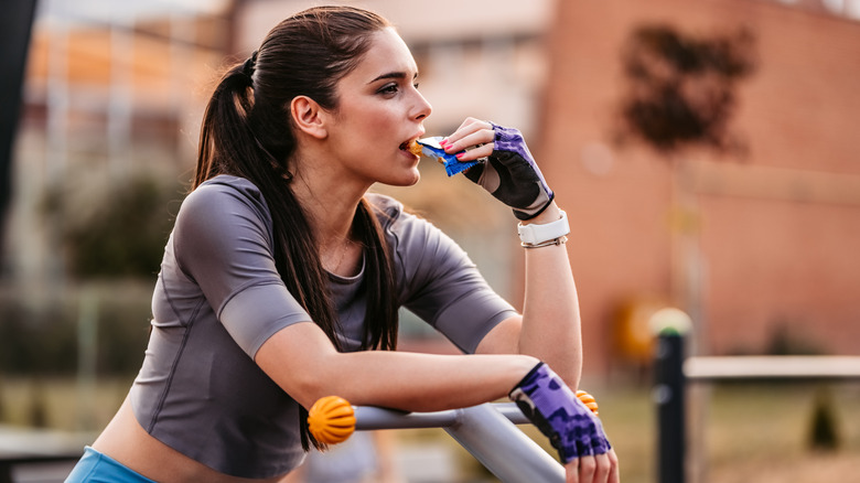 woman eating a protein bar while on a weight machine