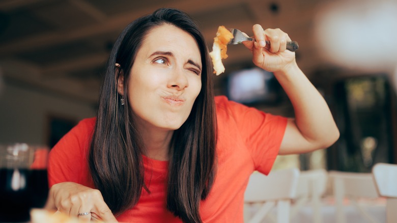 woman looking closely at the food on her fork