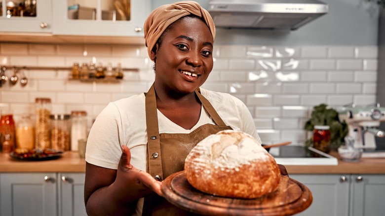 A woman offers a homemade loaf of sourdough bread