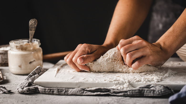 hands kneading dough with sourdough starter