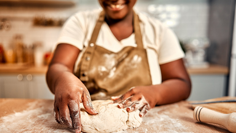 woman kneading and shaping bread dough in kitchen