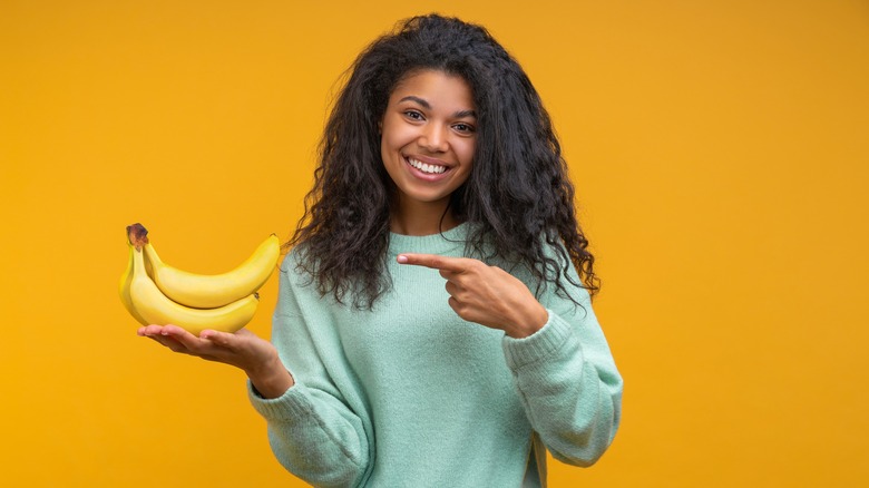 Woman pointing to and holding bananas